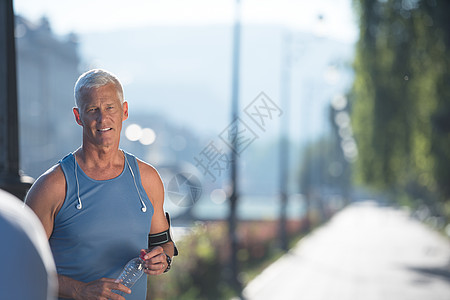 英俊的高级慢跑男子的肖像,同时放松休息后,晨跑图片