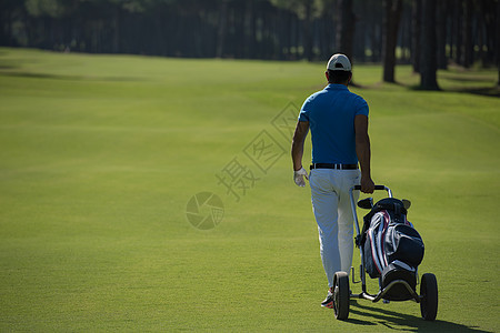 美丽的阳光明媚的天,英俊的中东高尔夫球员带着车轮袋球场上行走图片
