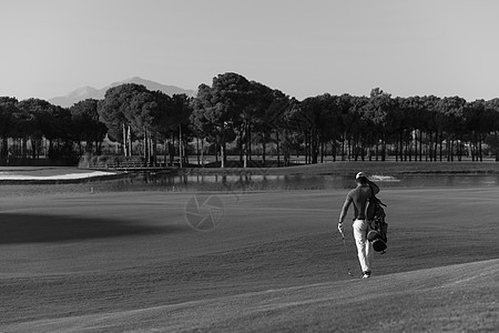 英俊的中东高尔夫球手背着包,走高尔夫球场的下个洞图片