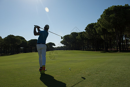 高尔夫球手击球与球杆美丽的早晨与太阳耀斑背景图片
