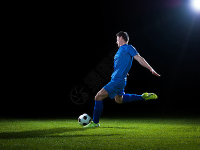 足球运动员足球场上踢球,黑色背景上被隔离图片