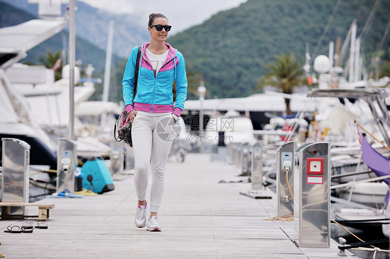 轻松的轻女人码头上散步,游乐场里游艇图片