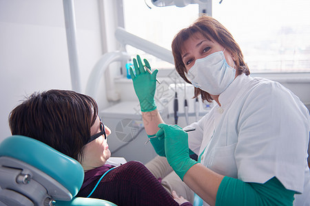 名妇女病人牙医的特写镜头,等待与背景中的女医生进行检查图片
