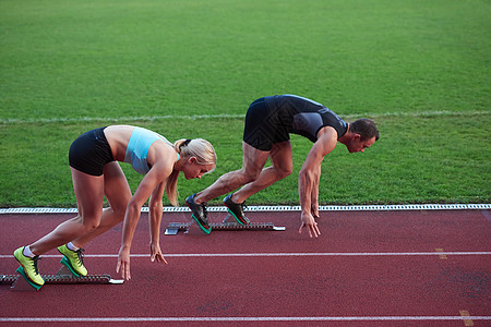 运动员女子体足球场上的田径跑道上跑步,代表体育中的竞争领导理念图片