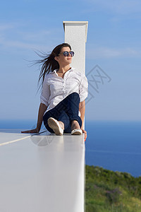 阳光明媚的天,放松的轻美丽的女人阳台上的豪华现代家庭别墅前图片
