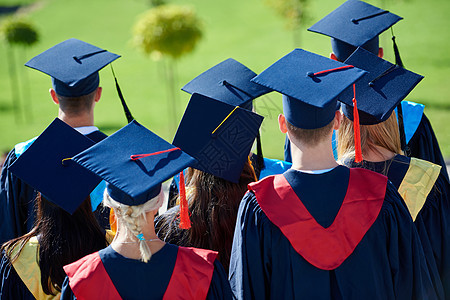 毕业日,轻的毕业生们站大学大楼前图片