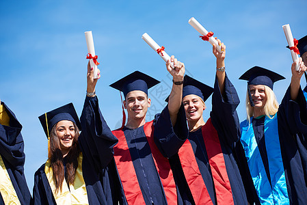 毕业日,轻的毕业生们站大学大楼前图片