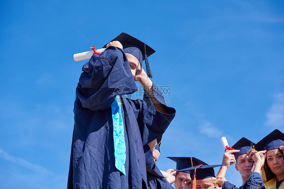 毕业日,轻的毕业生们站大学大楼前图片