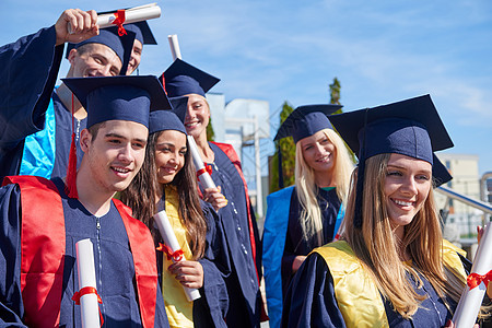 毕业日,轻的毕业生们站大学大楼前图片