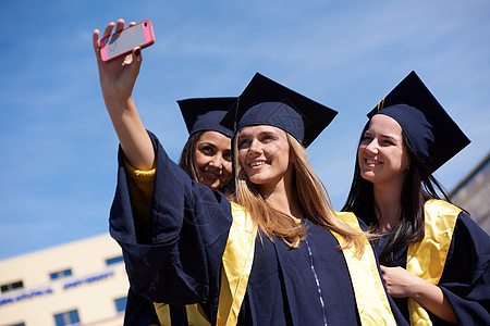 捕捉个快乐的时刻学生们聚集大学毕业生穿着毕业礼服,拍自拍照片图片