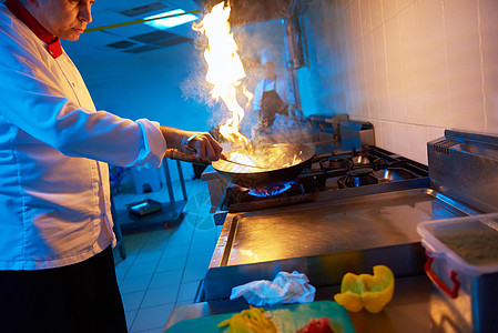 酒店厨房的厨师用火准备蔬菜食品图片