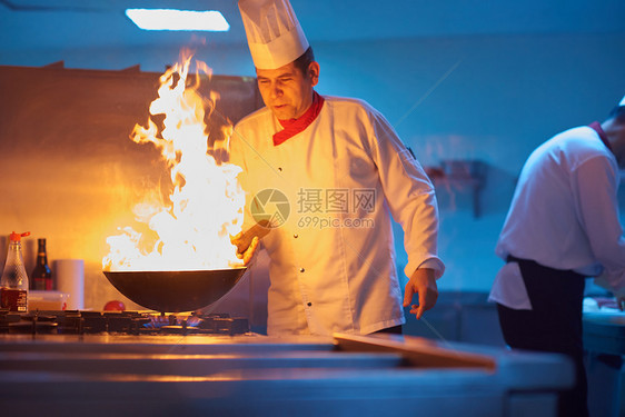 酒店厨房的厨师用火准备蔬菜食品图片