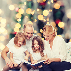 爱读书的孩子家庭,童,假期人微笑的母亲,父亲小女孩客厅诞树背景上看书背景