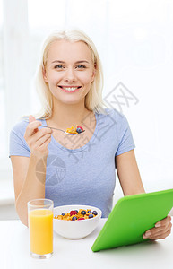 健康的饮食,饮食人的微笑的轻妇女与平板电脑家里吃早餐图片