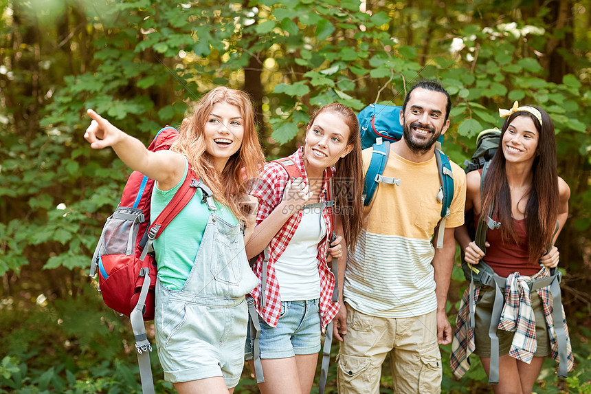 冒险,旅行,旅游,徒步旅行人们的群微笑的朋友,背包指着树林旅游业背包