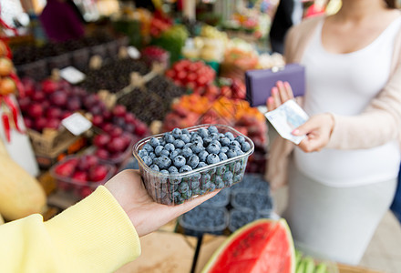 销售,购物,怀孕人们的密切孕妇与钱包金钱购买蓝莓街头食品市场图片