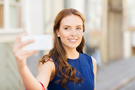 技术人的快乐的轻女人与智能手机自拍城市街道快乐的女人城市用智能手机自拍图片