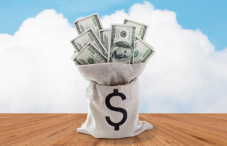 商业金融投资储蓄现金木地板蓝天背景上把美元纸币装袋子里背景图片