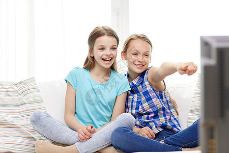 人,孩子,电视,朋友友谊的两个快乐的小女孩家里看电视指指点点图片