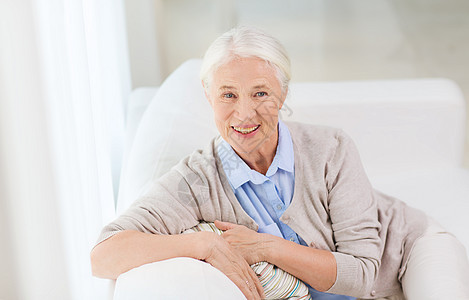 龄人的快乐微笑的老妇女坐家里的沙发上快乐的高级女人家图片