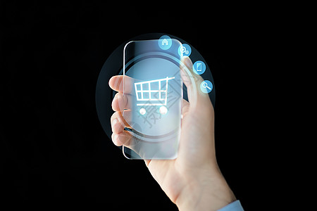 商业,未来的技术人的近距离的男手握透明的智能手机与购物车图标屏幕上的黑色背景图片
