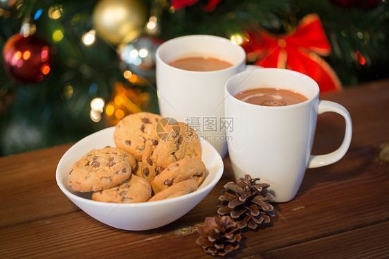 假日,冬天,食物饮料的燕麦片饼干,杯子与热巧克力可可饮料松果木制桌子上的诞树背景图片