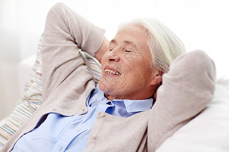 龄,放松人的快乐的微笑老妇女躺沙发上,家梦图片