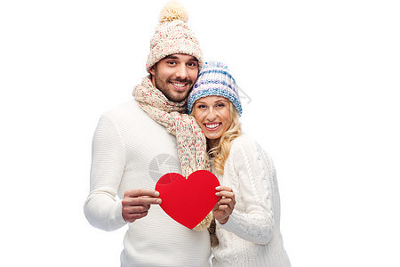 爱情,情人节,情侣,诞节人的微笑的男人女人戴着冬天的帽子围巾,着红色的纸心形图片