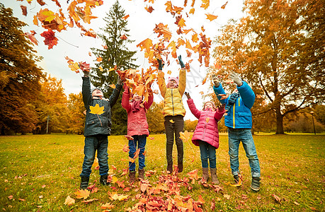 女孩和枫叶童休闲友谊人的群快乐的孩子玩秋天的枫叶,公园里玩得很开心背景