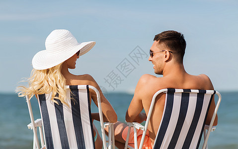 爱情,旅行,旅游,夏天人的微笑的夫妇度假穿着泳装坐椅子上,后海滩上晒太阳图片