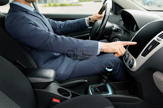 运输,商务旅行,技术人的轻人穿着西装驾驶汽车,并指着仪表盘上空白的黑色计算机屏幕图片
