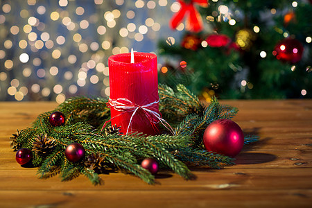 诞节装饰假日广告木板上用红色燃烧蜡烛天然绿色冷杉枝花环图片