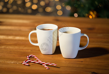 节日,诞节,冬天,食物饮料的糖果罐杯子与热巧克力可可饮料木制桌子上的诞树灯图片