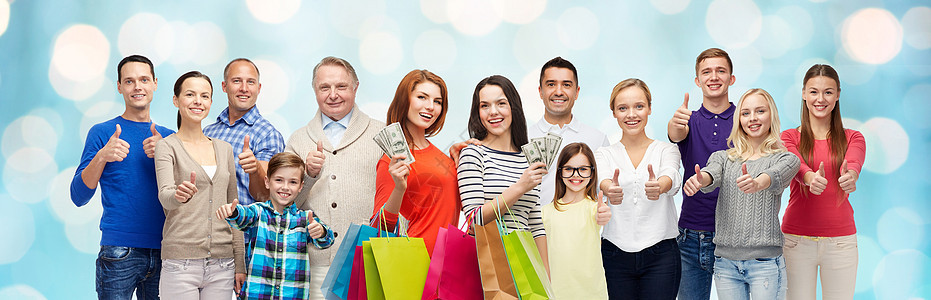 手势,销售,购物人的群微笑的男人,女人孩子展示竖大拇指,着购物袋与钱蓝色假日灯光背景图片