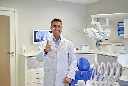 人,医学,口腔医学保健快乐的中男牙医穿着白色外套,牙科诊所办公室竖大拇指图片