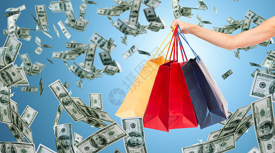 人,消费主义,金融销售特写女手购物袋蓝色背景金钱雨图片