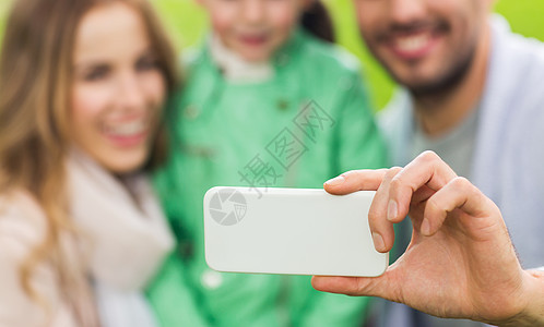 家庭,童,技术人的接近快乐的父亲,母亲小女儿公园用智能手机自拍图片
