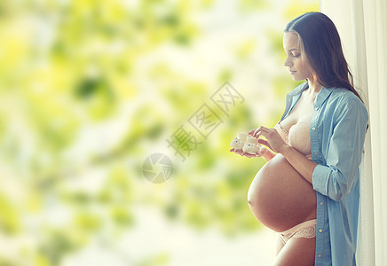 怀孕,母亲,人期望的快乐的孕妇大裸肚子抱着小婴儿家里绿色的自然背景图片