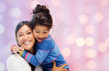 家庭,孩子,爱快乐的人的快乐的母亲女儿拥抱节日的灯光背景图片