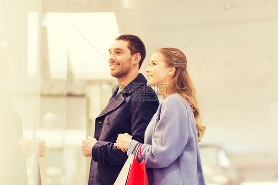 销售,消费主义人们的快乐的轻夫妇与购物袋,寻找商店橱窗商场图片
