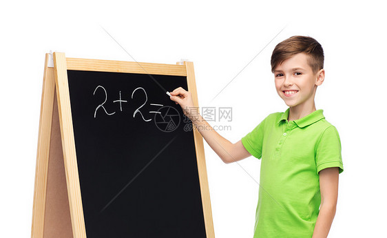 童,教育,学校,广告人的快乐的微笑男孩绿色马球T恤解决数学任务的空白学校粉笔黑板图片