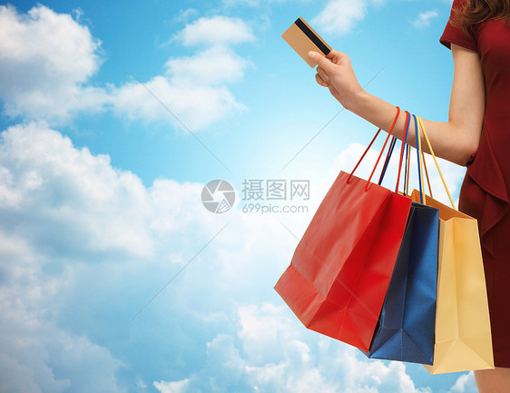 人,销售消费主义的近距离的女人与购物袋银行信用卡蓝天云彩的背景图片