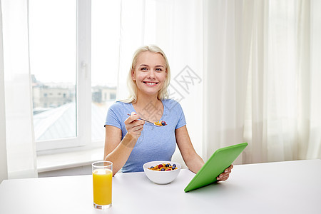 健康饮食,饮食,技术人的微笑的轻妇女与平板电脑电脑家里吃早餐图片