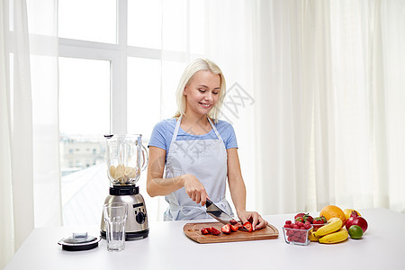 微笑的女人切水果放搅拌机里图片