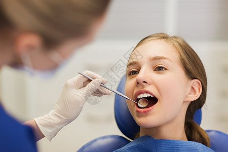 女牙医检查病人牙齿图片