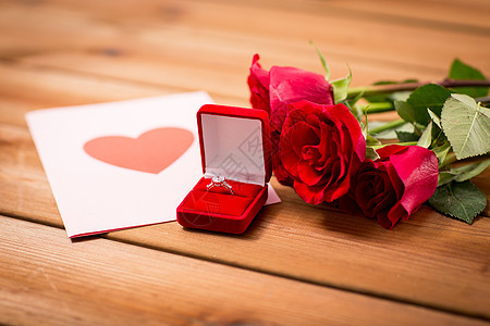 爱情,求婚,情人节假期的礼品盒与钻石订婚戒指,红色玫瑰贺卡木材上图片