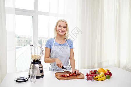 健康的饮食,烹饪,素食,饮食人们的微笑的轻女人与搅拌机切水果浆果家里的水果奶昔图片