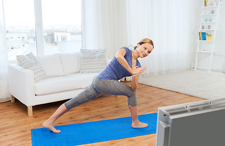 健身,运动,人健康的生活方式妇女瑜伽低角度弓步姿势垫子看电视课图片