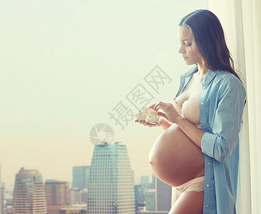 怀孕,母亲,人期望的快乐的孕妇大裸肚子抱着小婴儿家里的城市背景图片
