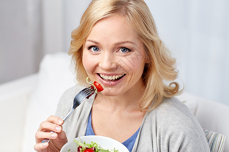 健康饮食人们的观念微笑的轻女人家吃蔬菜沙拉图片